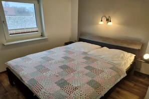 A bedroom with a bed, a window with blinds, a nightstand, and a wall-mounted light fixture. - Holiday apartment in Gager with swimming pool (Gager)