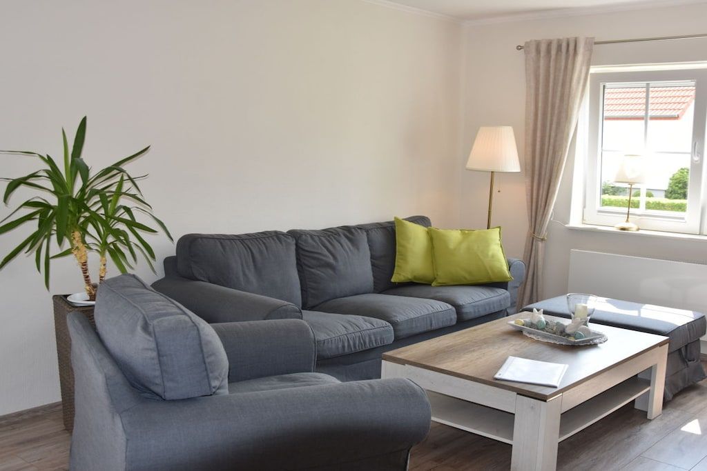 Un salon moderne avec un canapé gris, une table basse en bois et une plante en pot.