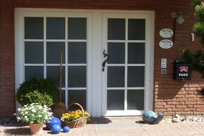 A building entrance with a double door, a basket of flowers, and a sign on the wall. - Wendt Forestry House "Waldblick" (Timmendorfer Strand)