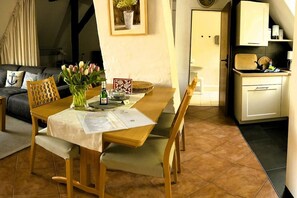 A dining area with a wooden table, chairs, a vase of flowers, and a framed picture on the wall. - Wendt Forestry House "Waldblick" (Timmendorfer Strand)