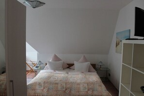 A bedroom with a bed, pillows, a small table, and a TV mounted on the wall. - Wendt Forestry House "Waldblick" (Timmendorfer Strand)