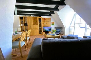 A living room with a television, a sofa, and a dining area with chairs and a table. - Wendt Forestry House "Waldblick" (Timmendorfer Strand)