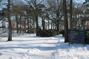 A snow-covered path with a directional sign indicating nearby locations. - Wendt Forestry House "Waldblick" (Timmendorfer Strand)