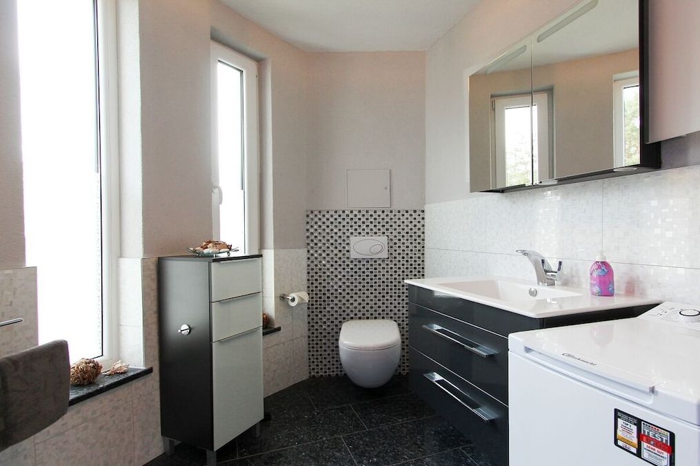 Une salle de bain moderne équipée de toilettes, d’un lavabo et d’un meuble de rangement.