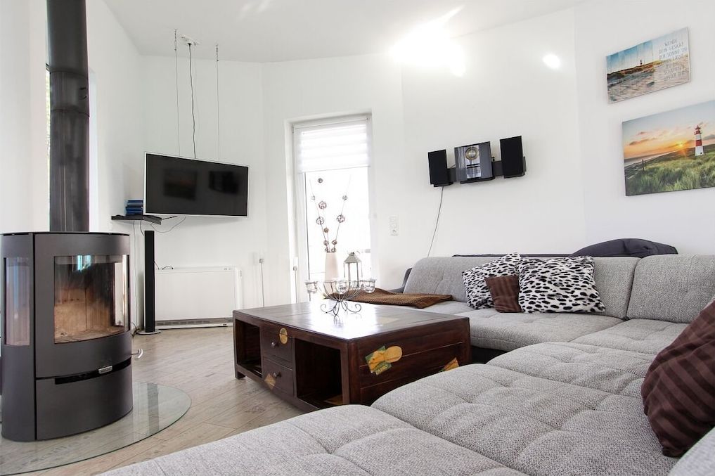 A living room with a fireplace, a sofa, a coffee table, and a TV mounted on the wall.