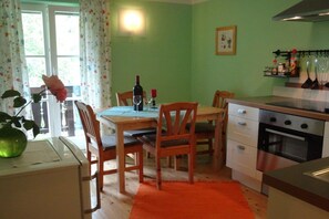 A kitchen with a dining table, chairs, a stove, and a refrigerator. - Landhaus Arztmann - Fewo Linde (Bodensdorf am Ossiacher See)