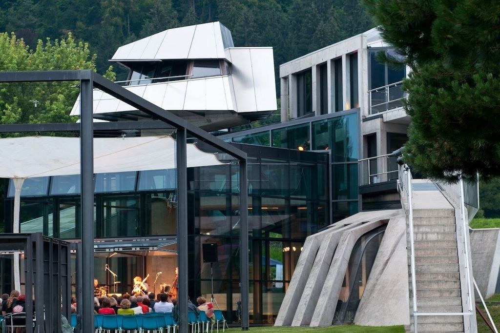 A modern building with a glass facade and a unique architectural design, featuring a stage for performances.