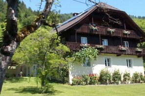 A traditional chalet with a sloped roof, wooden balconies with flower boxes, and a well-maintained garden. - Landhaus Arztmann - Fewo Linde (Bodensdorf am Ossiacher See)