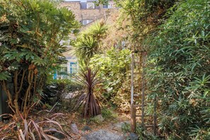 A garden with various plants and a wooden structure. - New! 2BR Garden Flat by Victoria Park (Greater London)
