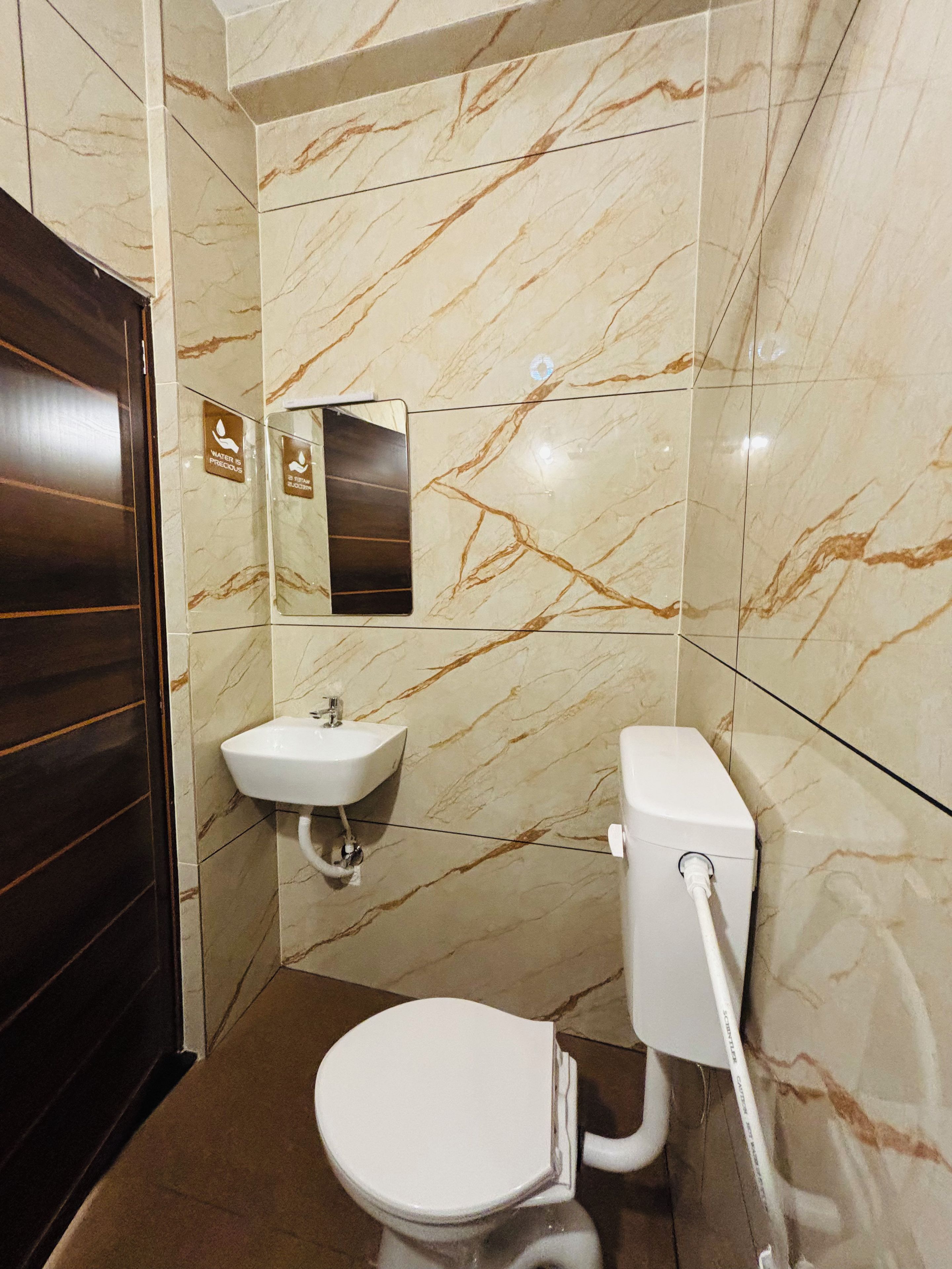 A bathroom with a toilet, sink, and mirror.