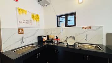 Una cocina moderna con dos fregaderos, encimeras negras, salpicadero de mármol y una ventana con vistas.