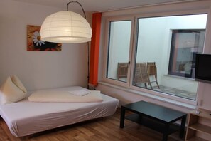 A bedroom with a bed, a bedside table, a window with a view of outdoor furniture, and a ceiling light fixture. - Holiday apartment with 2 bedrooms (Dorfgastein)