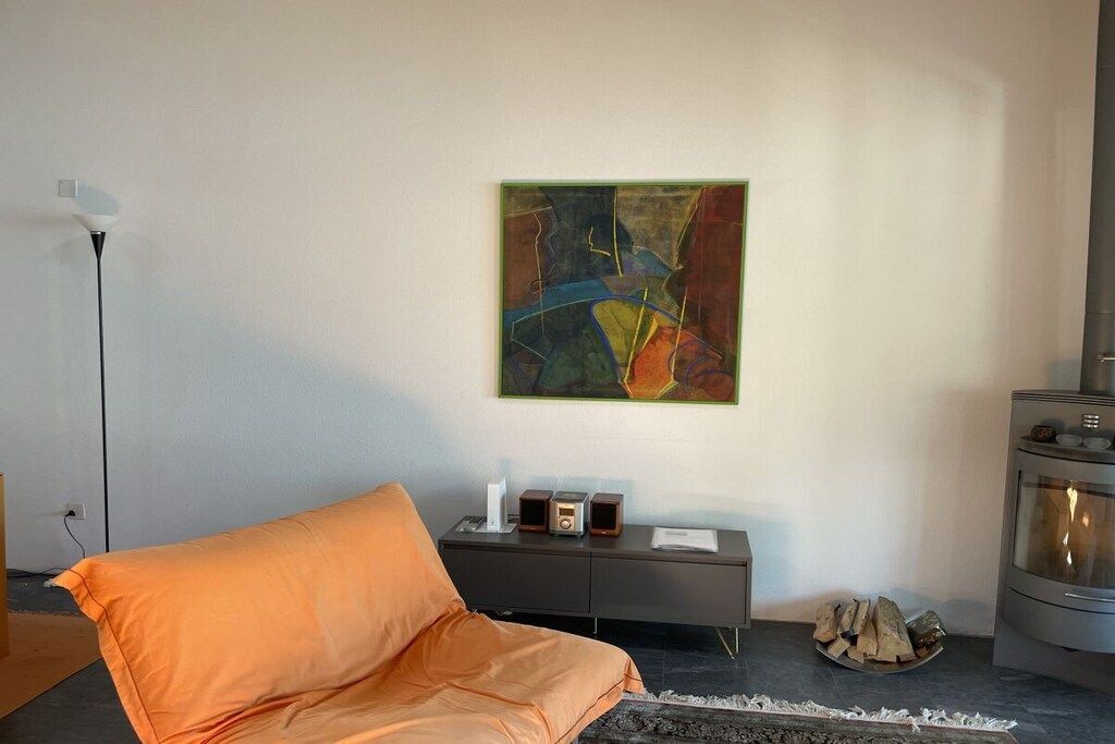 A modern living room with a sofa, a fireplace, a painting on the wall, and a small cabinet with speakers.