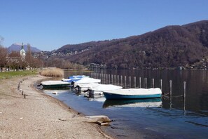 Blick auf einen See mit angestaubten Booten, einer Kirche und einem Berg im Hintergrund.