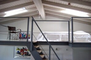 Ein Schlafsaalzimmer mit Etagenbett, einer Treppe und einem gerahmten Kunstwerk an der Wand.