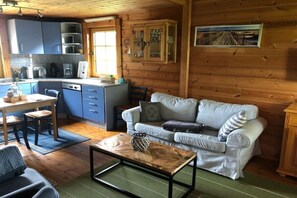 A compact living space with a kitchenette, a sofa, a coffee table, and a dining area. - Holiday home in Kappeln with swimming pool (Kappeln)