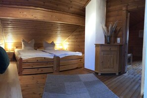 A wooden room with a bed, bedside lamps, a cabinet, and a rug. - Holiday home in Kappeln with swimming pool (Kappeln)