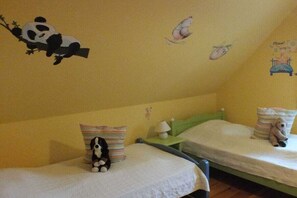 Ein Kinderzimmer mit zwei Betten, jedes mit einem Kopfkissen und einem Stofftier.