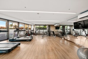 A modern gym with cardio machines, weight stations, and a large mirror wall. - Westlight by Aryve | Surfers Paradise (Surfers Paradise)