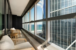 A modern interior with large windows, wicker furniture, and a view of the ocean and a tall building. - Westlight by Aryve | Surfers Paradise (Surfers Paradise)