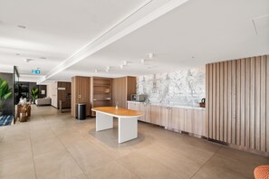 A modern reception area with a marble wall, wooden paneling, and a central table. - Westlight by Aryve | Surfers Paradise (Surfers Paradise)
