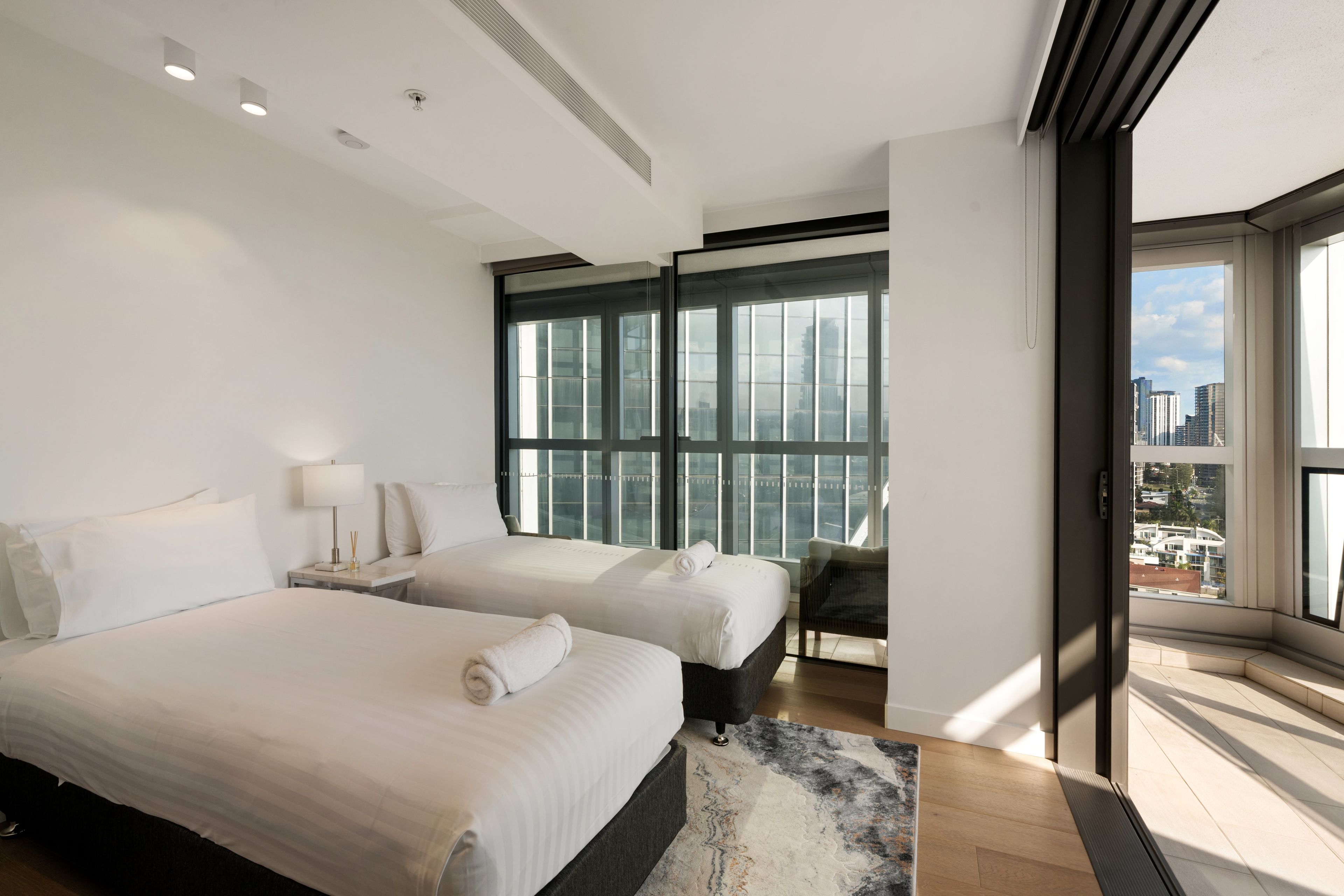 Une chambre d’hôtel moderne avec deux lits, une grande fenêtre et une vue sur la ville.
