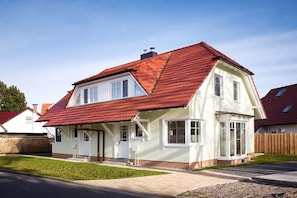 A two-story house with a red-tiled roof, white exterior walls, and a front porch. - Holiday home in Zingst with swimming pool (Zingst)