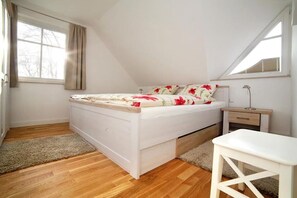A bedroom with a bed, a nightstand, a lamp, and a window. - Holiday home in Zingst with swimming pool (Zingst)