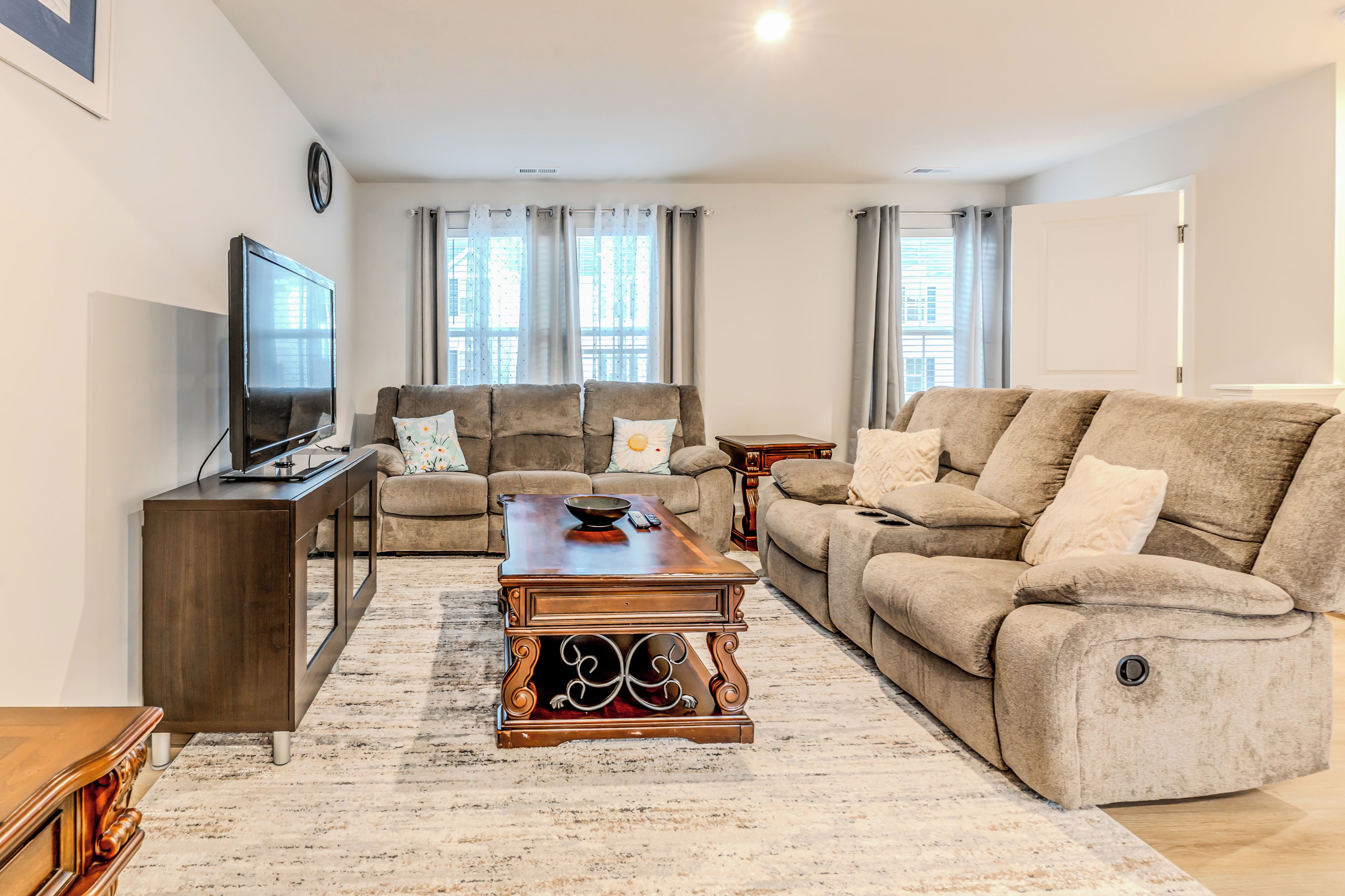 A living room with a sofa, a coffee table, a TV, and a clock on the wall.