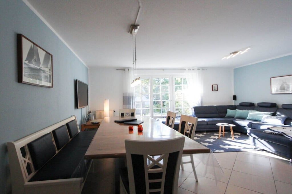 Ein modernes Wohnzimmer mit Essbereich, einer Sofagarnitur und einem Fernseher.