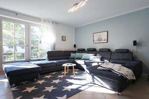 A modern living room with a sectional sofa, a small round table, and a star-patterned rug. - Holiday home in Zingst with swimming pool (Zingst)