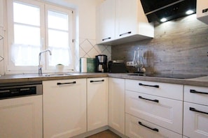 A kitchen with white cabinets, a dishwasher, a coffee maker, and a toaster. - Holiday home in Zingst with swimming pool (Zingst)