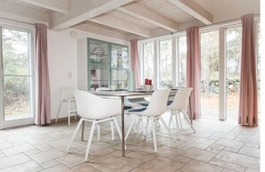 Ein Essbereich mit Tisch und Stühlen, einer Glasschrank und großen Fenstern mit Vorhängen.