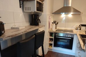 Une cuisine compacte équipée d’un four à micro-ondes, d’une machine à café, d’un four et d’un évier.