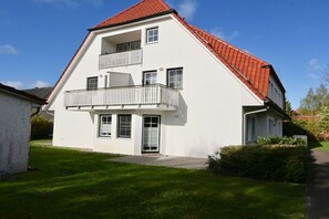 A two-story building with a red-tiled roof, a balcony on the upper floor, and a well-maintained lawn in front. - Meding Waldstraße 60b-1 (Prerow)