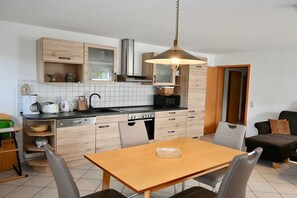 Eine moderne Küche mit Holzausstattung, einem Esstisch mit Stühlen und einer Pendelleuchte.