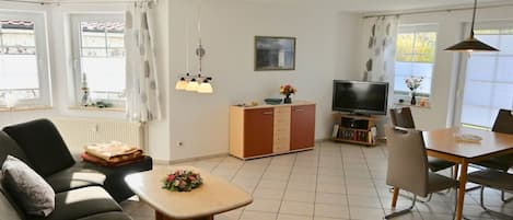 Un salon comprenant un canapé, un téléviseur, une table à manger et un meuble.