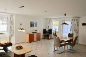 A modern living room with a dining table, sofa, TV, and decorative items. - Meding Waldstraße 60b-1 (Prerow)