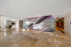 Un intérieur moderne avec un escalier en verre et un espace d’accueil.