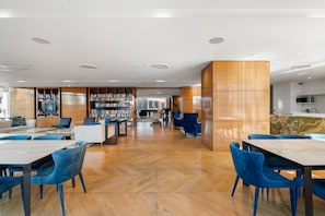 A modern library with wooden bookshelves, seating areas, and a marble counter. - Two Horizons by Aryve (Broadbeach)