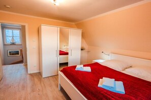 A bedroom with a bed, a wardrobe, a bedside table, and a window. - Holiday home with 2 bedrooms (Fuhlendorf)