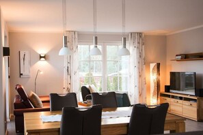 A modern dining area with a wooden table, black chairs, and pendant lighting. - Holiday home with 2 bedrooms (Fuhlendorf)
