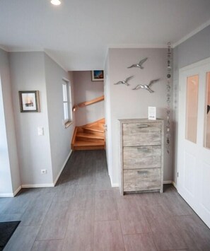 A hallway with a wooden staircase, a wall-mounted light fixture, and a door with a sign. - Holiday home with 2 bedrooms (Fuhlendorf)