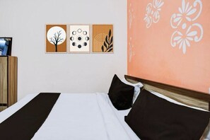 A bed with black and white bedding, a wooden headboard, and three framed artworks on the wall. - Hotel Shree Rudraksha (Varanasi)
