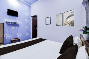 A bedroom with a bed, a TV mounted on the wall, and a door. - Hotel Shree Rudraksha (Varanasi)