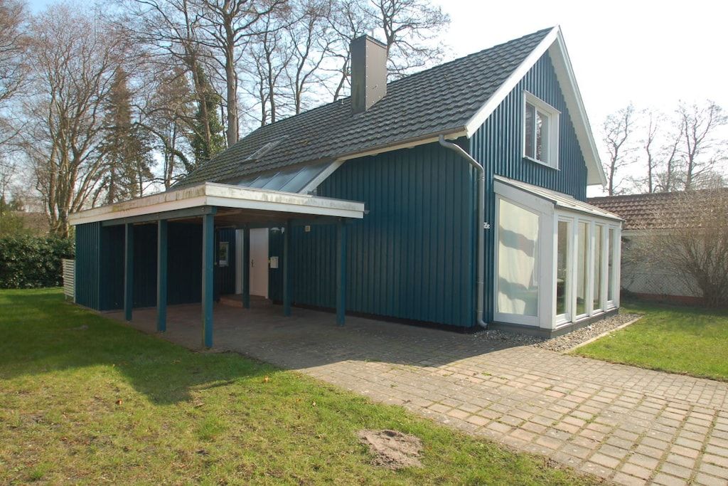 Een tweelaags huis met een overdekt terras en een groot raam op de tweede verdieping.
