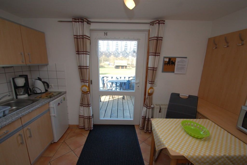 A compact kitchen with a sink, stove, and a small dining area with a table and chairs.