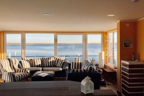 Ein Wohnzimmer mit Meerblick, ausgestattet mit gestreiften Sofas, einem Couchtisch und einer dekorativen Laterne.