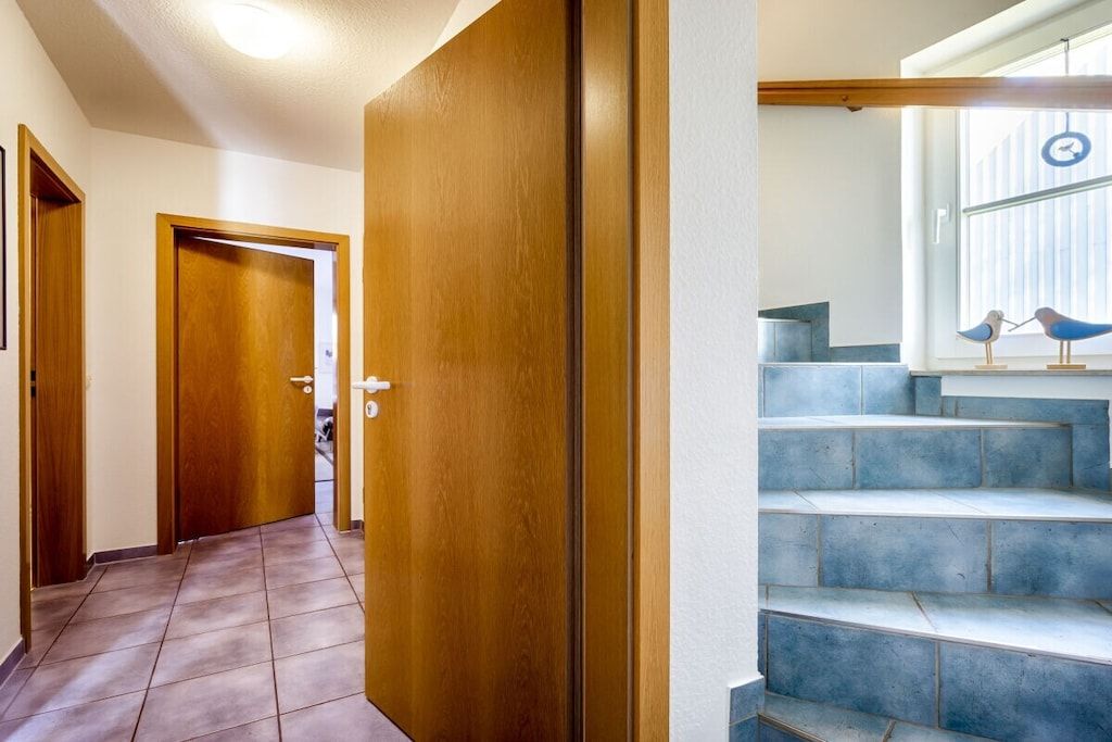 Ein Flur mit Holztüren und einer Treppe mit blauen Stufen.