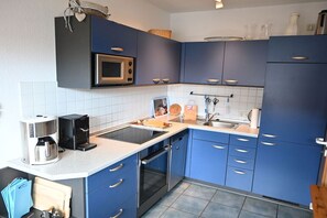 Eine moderne Küche mit blauen Schränken, einer Mikrowelle, einer Kaffeemaschine und einem Spülbecken.
